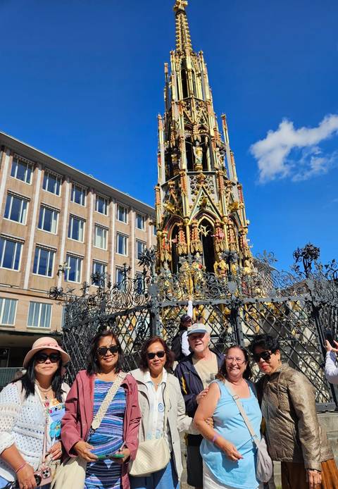 Ornate fountain surrounded by a decorative wrought iron fence.