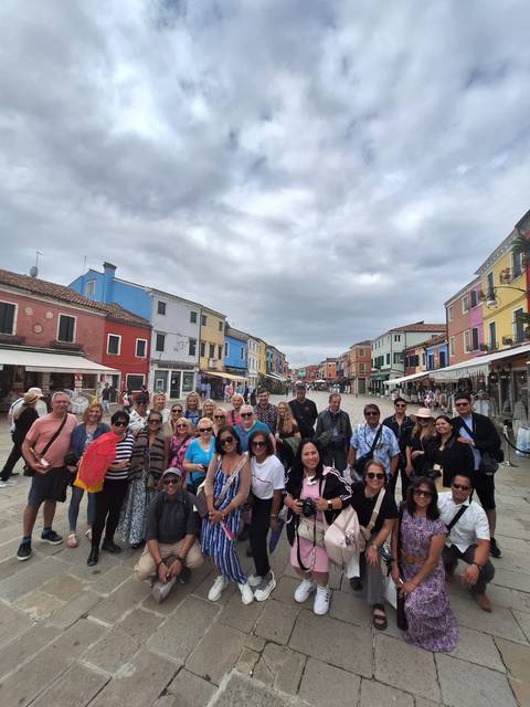 Group of people posing on a colorful street lined with shops.