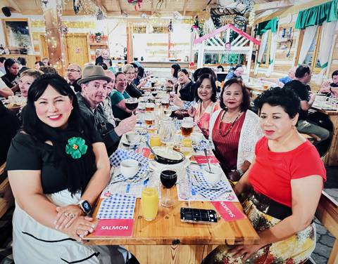       People sitting around a dining table enjoying a meal.
  