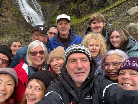       Selfie of a group of people dressed warmly with a waterfall in the background.
  
