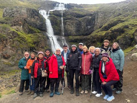 Group of people posing in front of a waterfall.