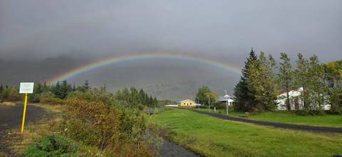 Vibrant rainbow stretching over a rural landscape with small houses.