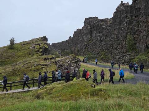       Group of people walking along a rocky path in a rugged landscape.
  