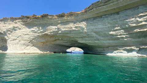 Natural white rock arch over clear green water.