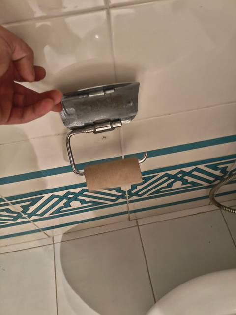 Empty toilet paper holder on a tiled wall.