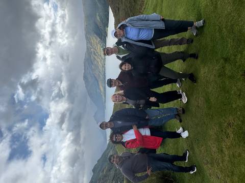       Group of people posing in front of a scenic lake view.
  