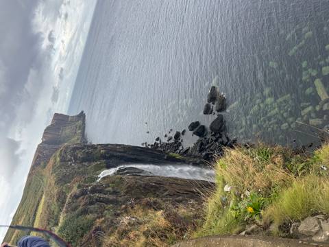 A cliffside with a waterfall dropping into the sea.