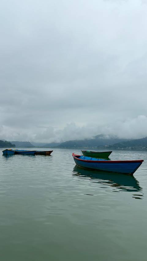 Colorful boats on a tranquil lake under a cloudy sky