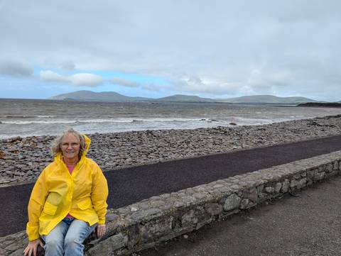 Woman in a yellow raincoat at a rocky beach