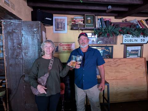 Two people holding drinks in a pub setting