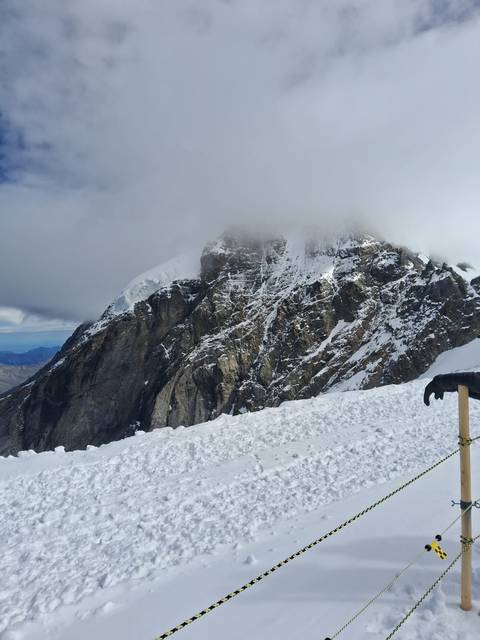 Snowy mountain peak partially covered by clouds