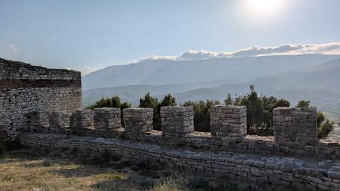       Historical stone wall with scenic mountain view in the background.
  