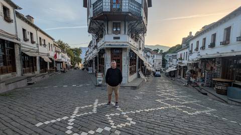       Person standing in the middle of a cobblestone street surrounded by historical buildings.
  