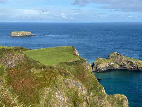 Coastal cliffs with green grass and blue ocean.