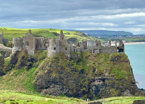       Dunluce Castle ruins on a cliffside with sea in the background.
  