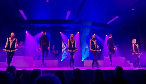 Dancers performing on stage with purple lighting.