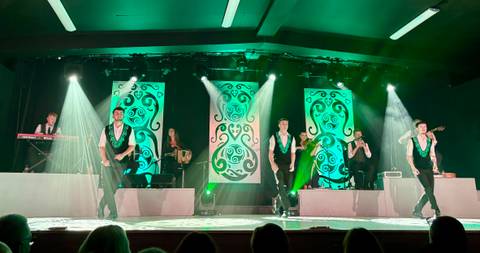 Performers on stage with green lighting and instruments.