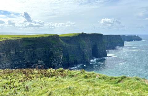       Expansive view of the Cliffs of Moher with waves crashing below.
  