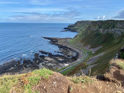       Coastal cliffs and ocean view with a winding road.
  