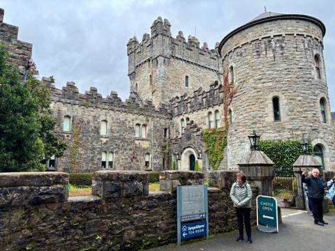 Castle with turrets, visitors outside.