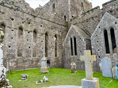       Old stone building with gothic details and gravestones.
  