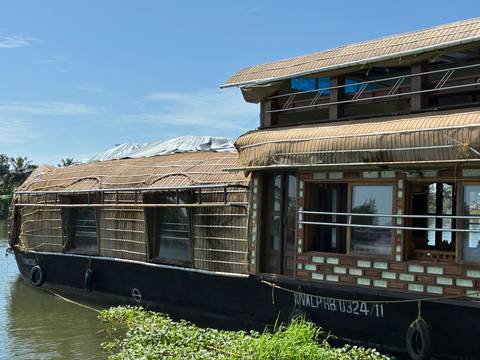 Houseboat with woven design docked on a river.