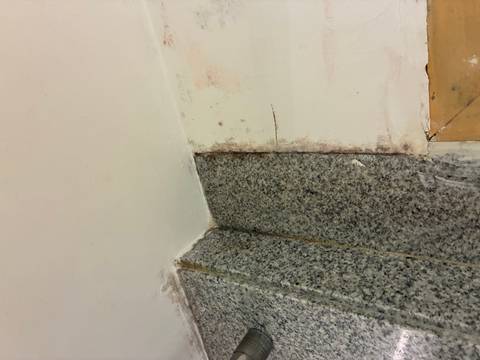 Corner of a wall with unfinished paint and granite.