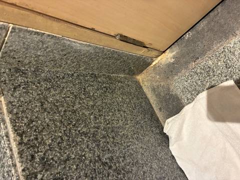 Bathroom floor with dirty tiles and a discarded towel.