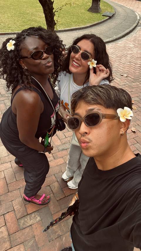 Close-up of a person wearing sunglasses and a flower, posing for a selfie.
