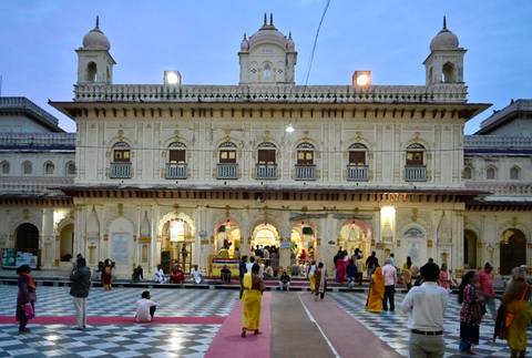 A large temple entrance with people walking and observing. Intricate architectural details visible.