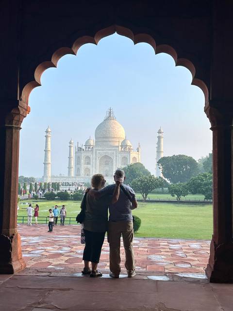 A couple admiring the Taj Mahal from a historical archway.