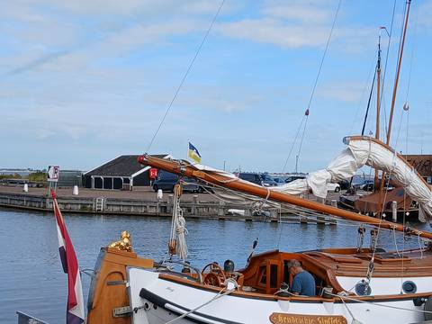Sailing boat in a harbor with national flags.
