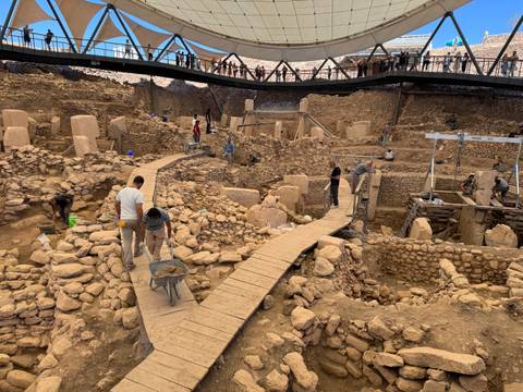       Archaeological site with people walking on pathways.
  