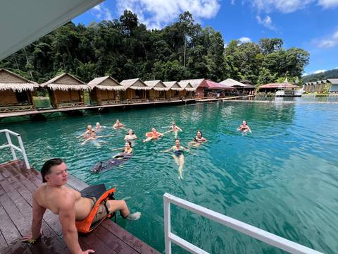 People swimming near floating bungalows over a lake.