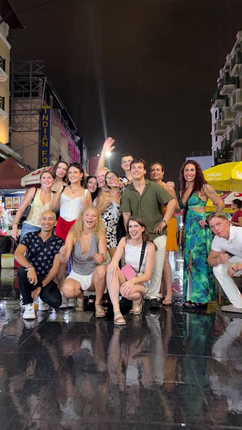Group of people posing on a lively street at night.
