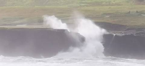 Waves crashing against cliffs in a misty coastal setting.