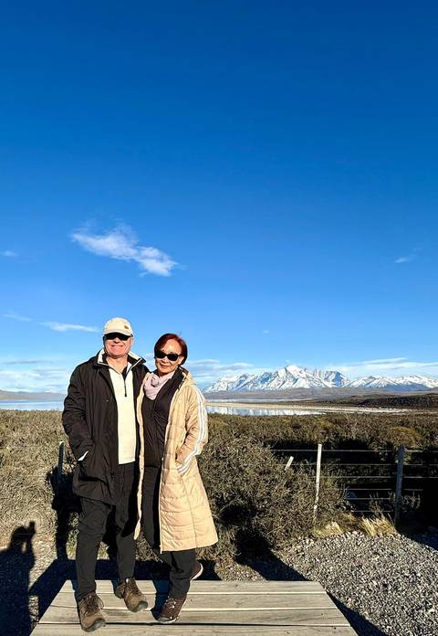 A couple posing with a snow-capped mountain landscape in the background.