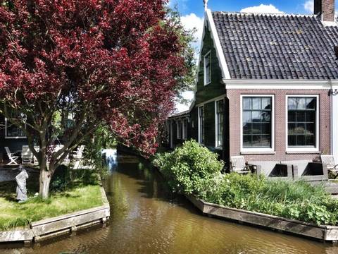 A picturesque canal with houses and lush red foliage.