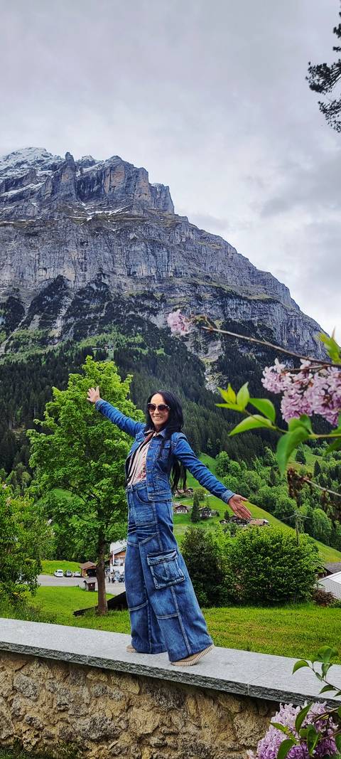 A woman joyfully posing with a mountain backdrop.