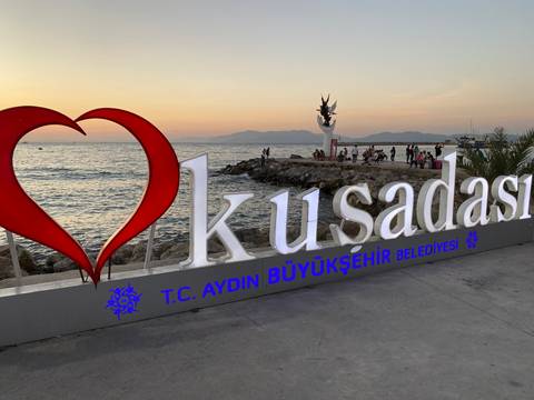 Waterfront promenade with a large sculpture and a love sign.