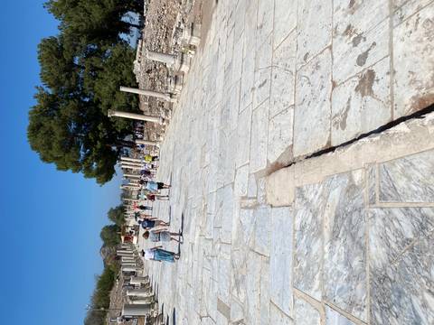       People walking between ancient marble columns.
  
