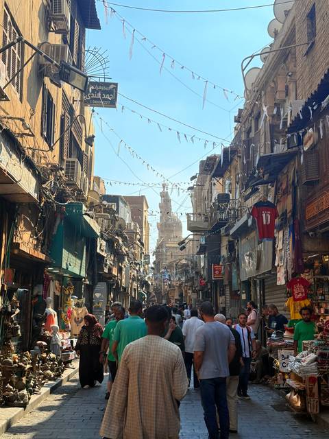Narrow bustling street with shops on both sides.