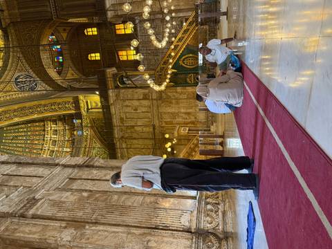 Interior of a mosque with people sitting and praying.