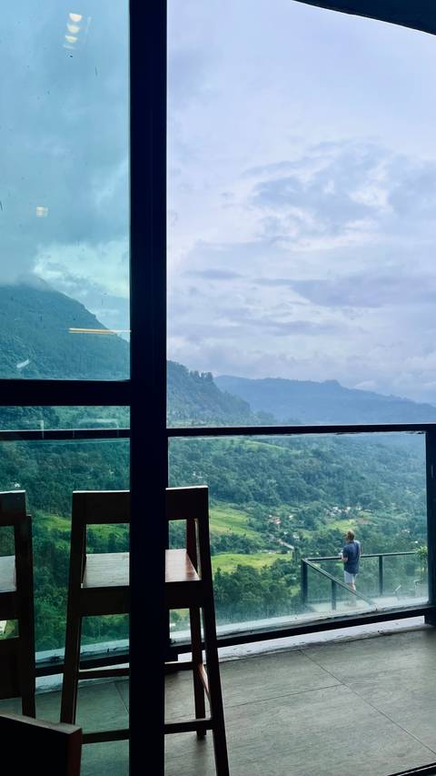 View from inside a building looking out at hills and cloudy sky.