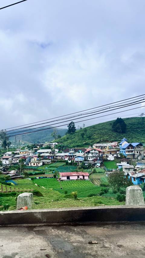       Small town surrounded by green hills and power lines.
  