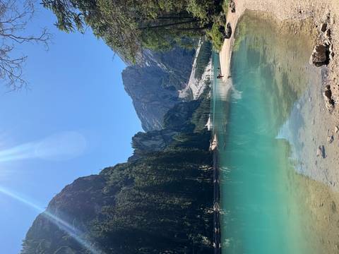       Scenic lake view with mountains and a clear blue sky.
  