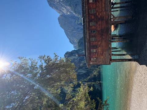       Wooden hut on a lake surrounded by a mountainous landscape.
  