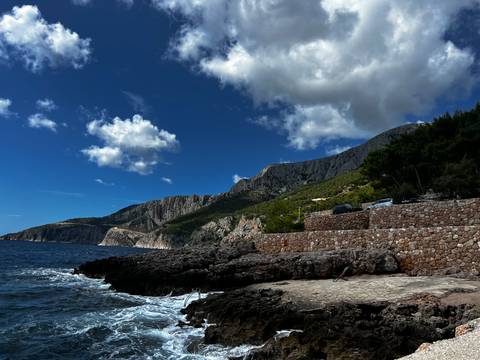 Rocky coastline with mountains and a blue sea.