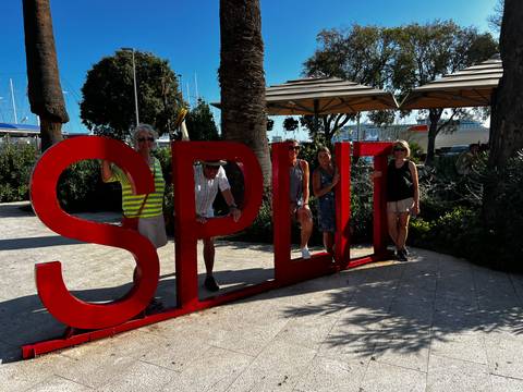 Tourists posing with the Split sign in a sunny park.