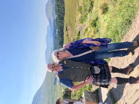 Two people posing with scenic mountainous background.
